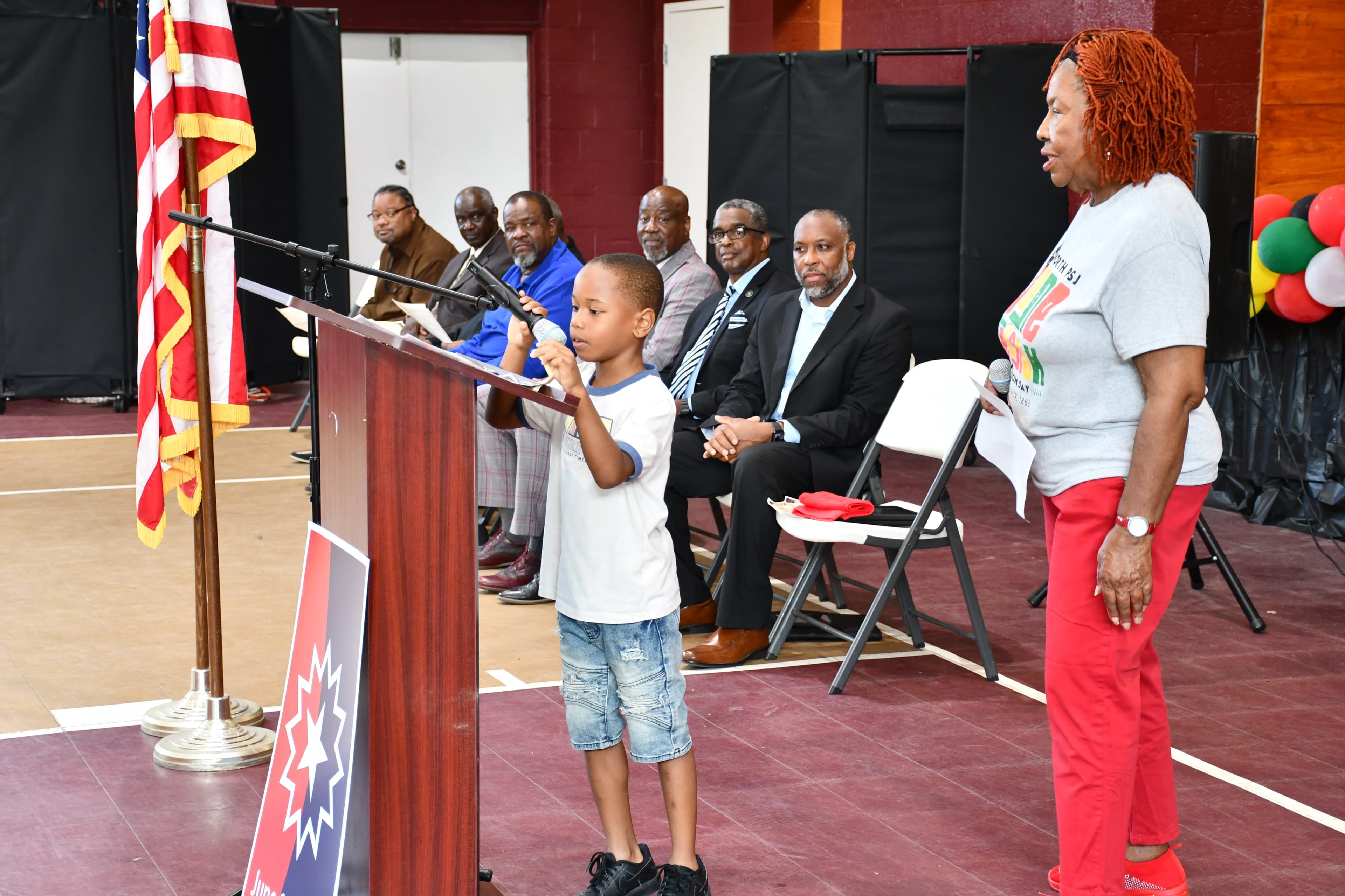 A young boy speaking into the microphone at the podium during the Juneteenth program