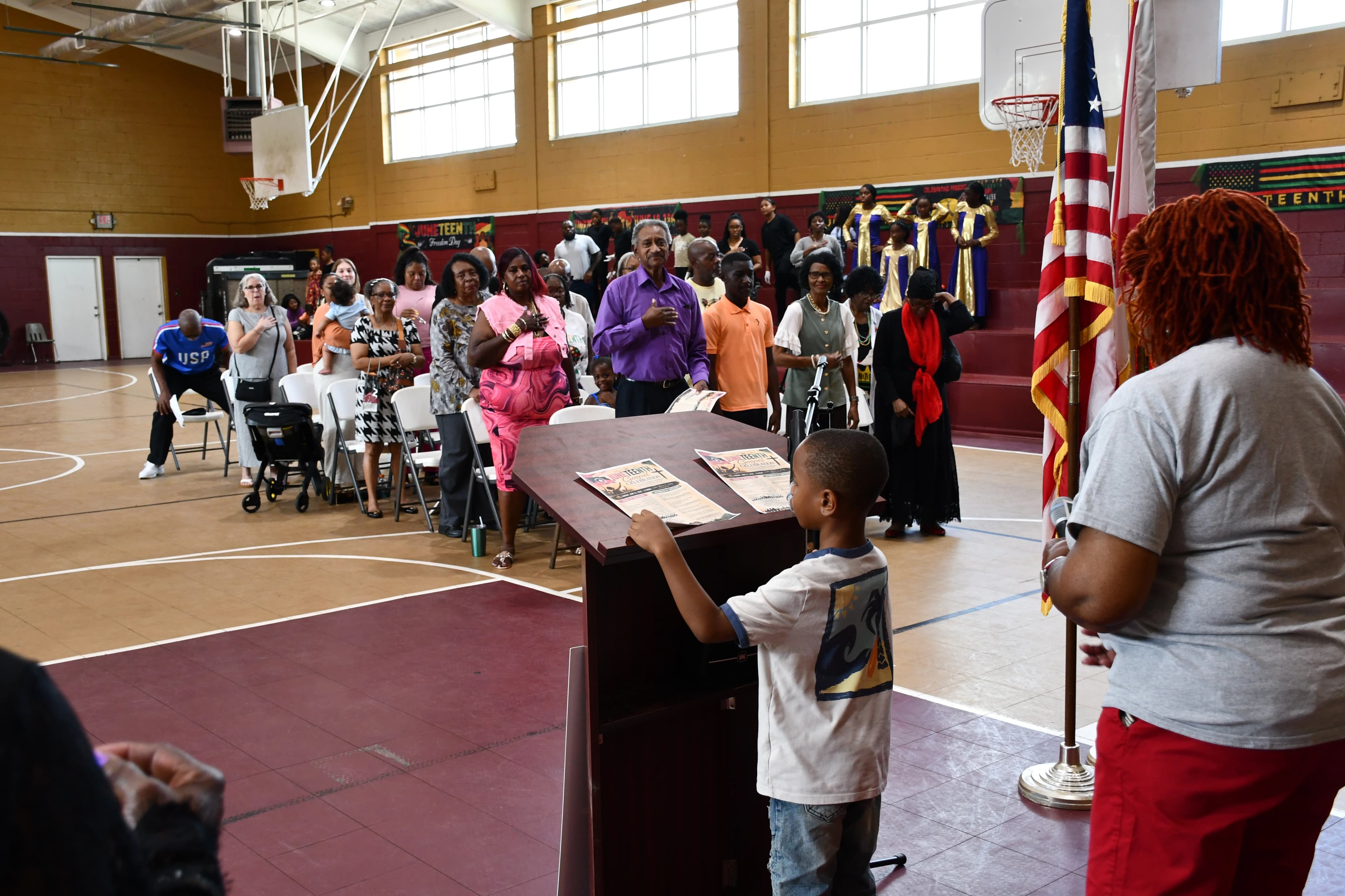 Attendees standing with the robed choir behind them during the Juneteenth ceremony at Washington High School
