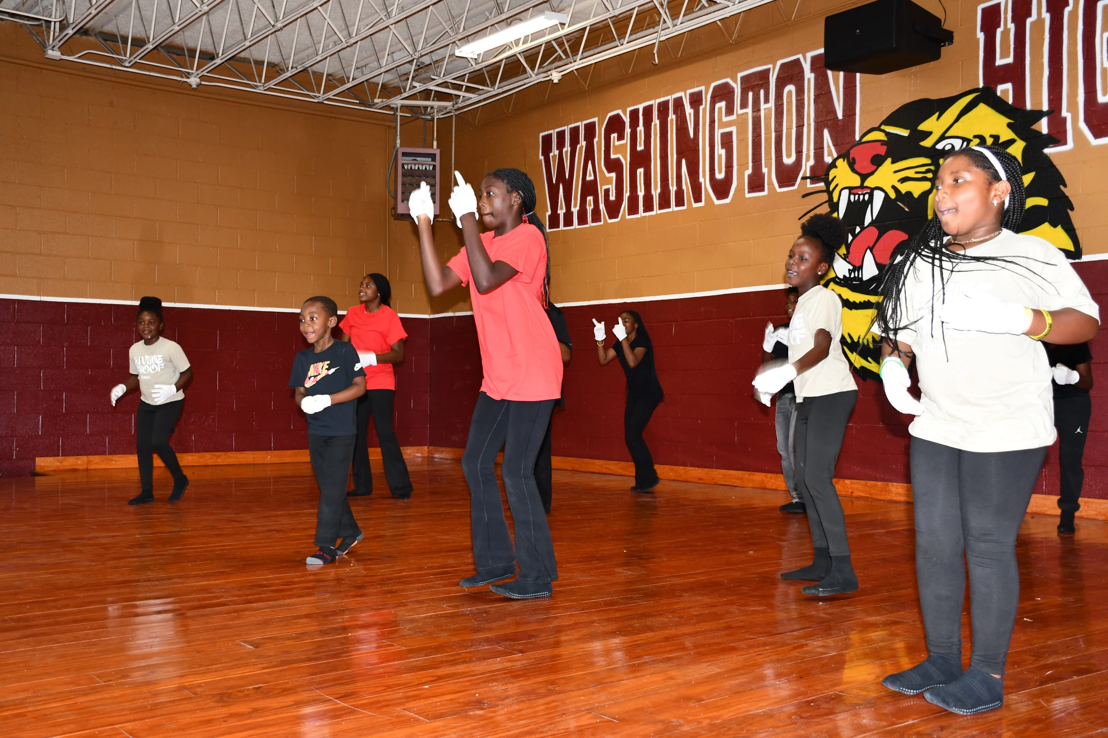 Children in white gloves performing a praise dance under the Washington High School mural