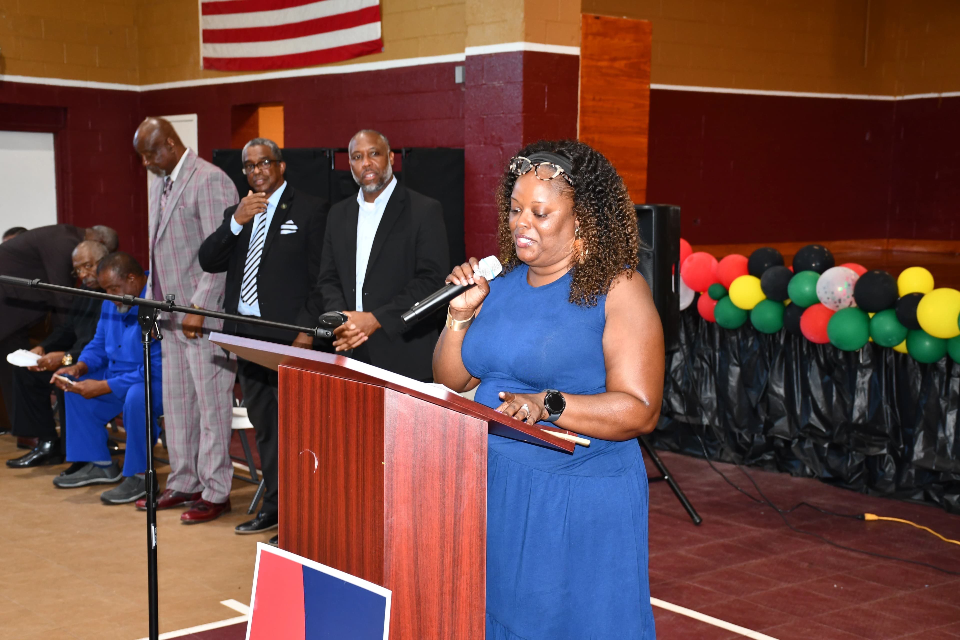 A woman speaking at the podium during the Juneteenth program with leaders standing behind her