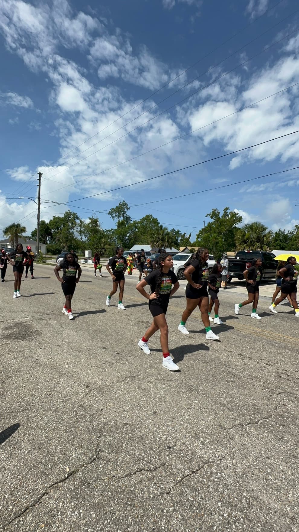 Youth performers in matching black Juneteenth shirts marching through the parade route