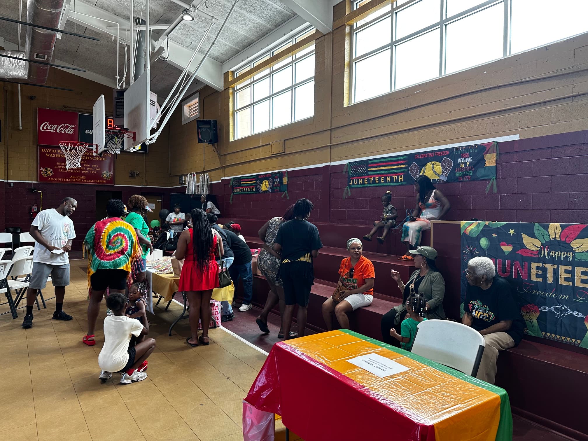 Wide view of the Washington High School gymnasium during the Juneteenth celebration with vendors and banners