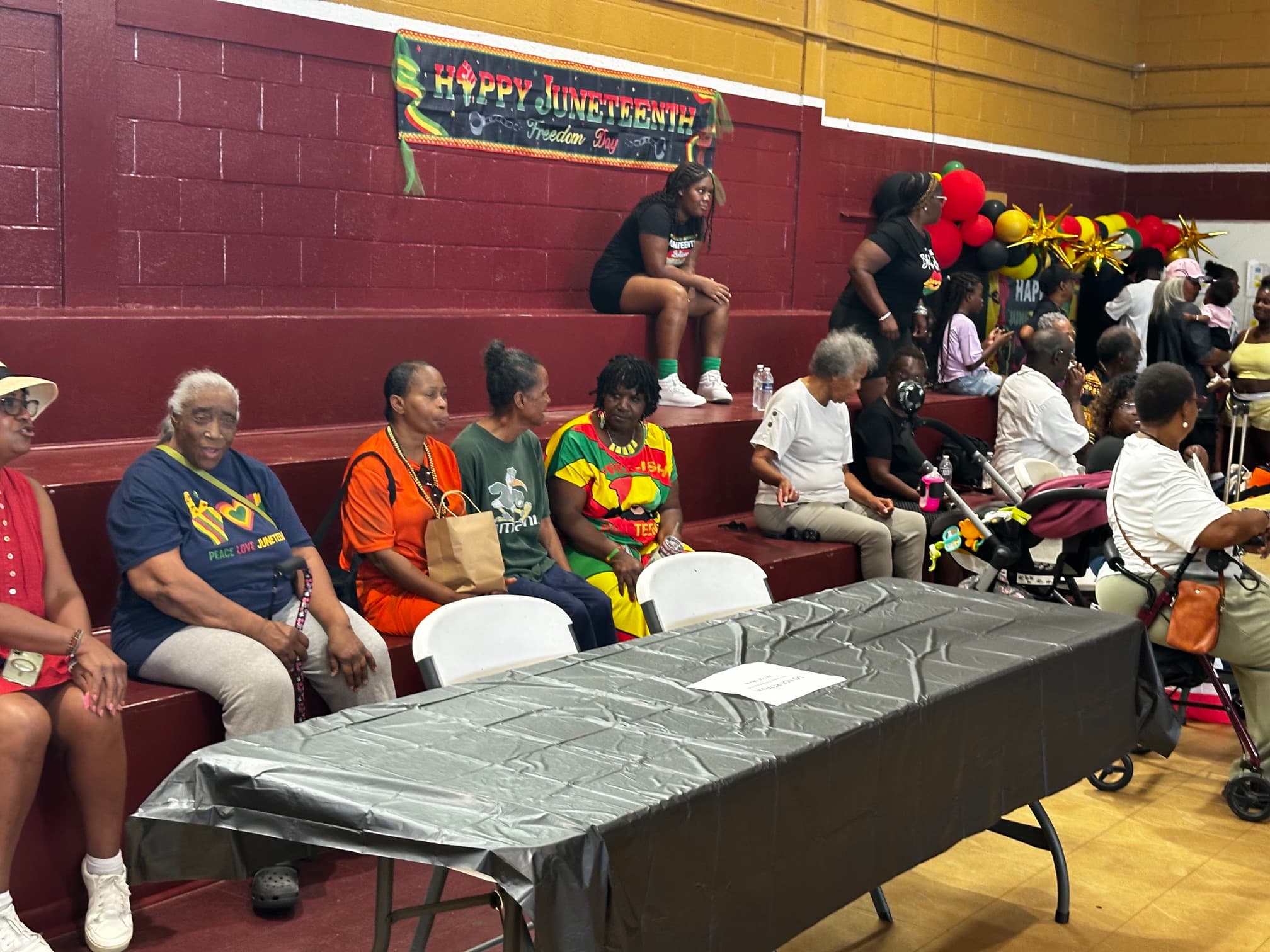 Attendees seated inside Washington High School gymnasium under a Happy Juneteenth Freedom Day banner