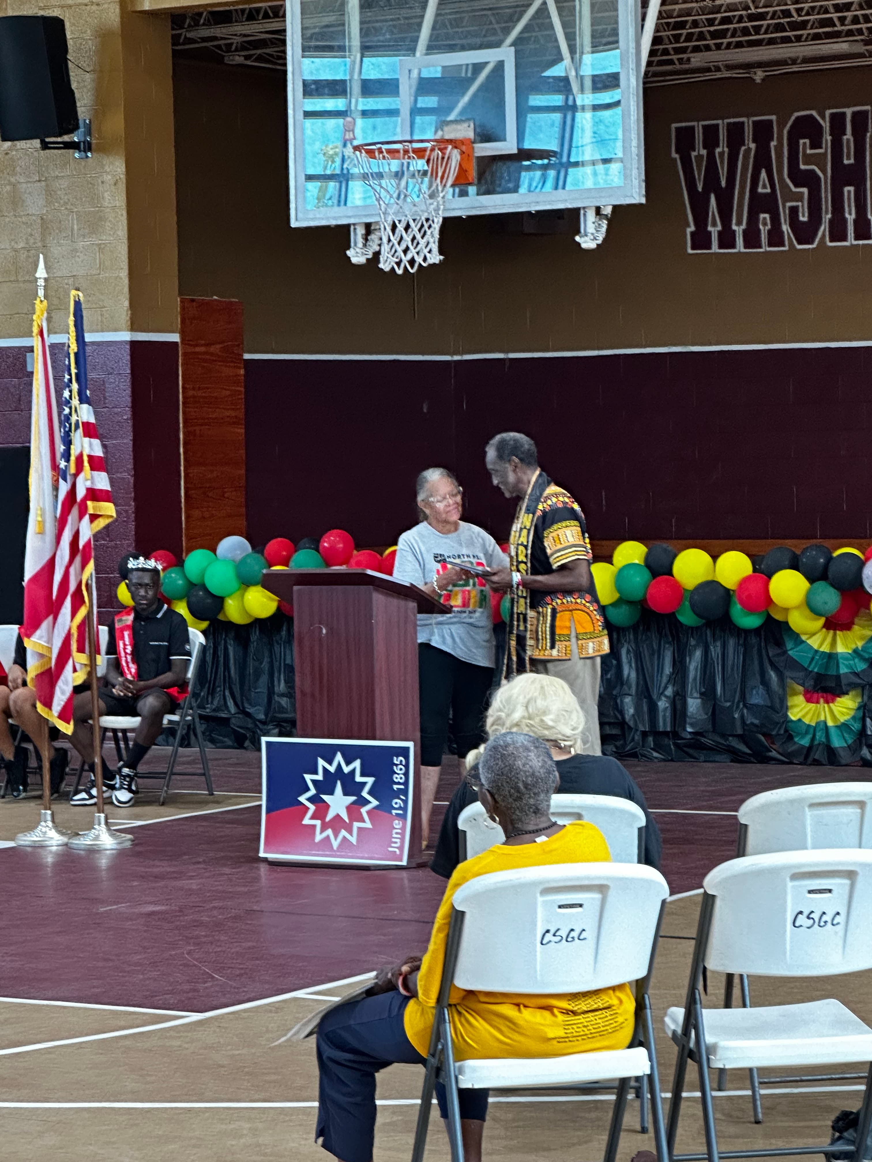 Speaker at the podium with the Juneteenth flag during the ceremony